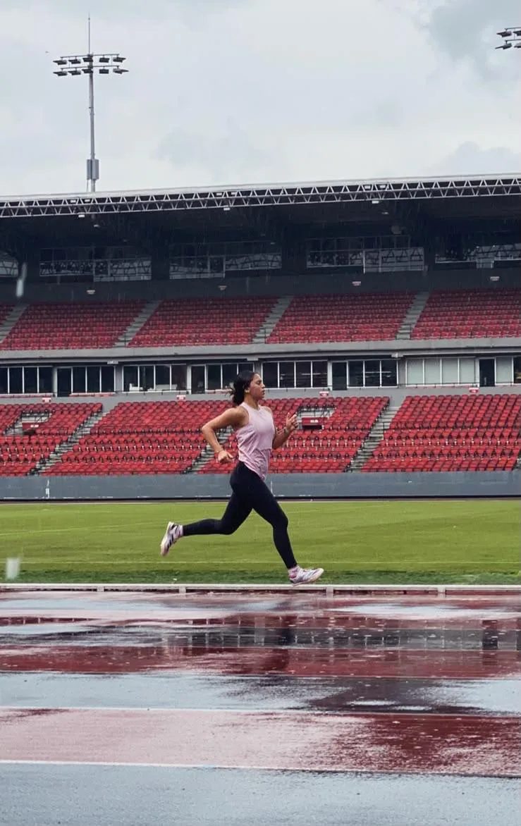 Atleta entrenando en la pista del estadio bajo la lluvia
